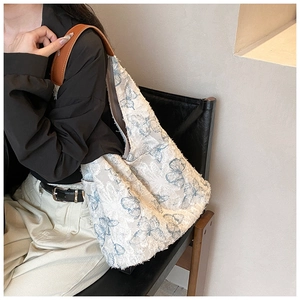 Detail of embroidered butterfly tote with brown leather straps and raw edges