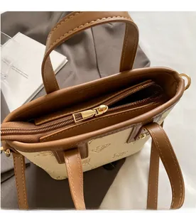 Detail of smooth gold zipper and bee print on canvas and leather bucket bag
