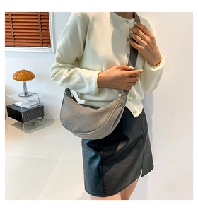 Detailed texture of gray corduroy dumpling bag with adjustable shoulder strap on model