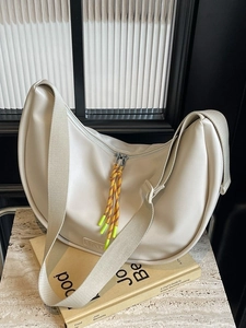 Sac bandoulière demi-lune beige chic avec détail de cordon tressé sur surface en marbre