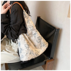 Detail of embroidered tote bag with blue butterfly patterns and leather shoulder strap