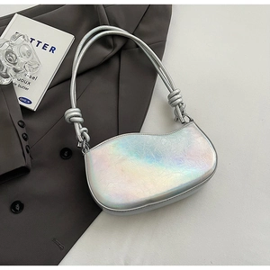 Detail of silver iridescent crescent bag featuring knotted strap and metallic texture