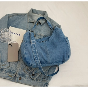 Gros plan sur la texture du denim délavé et la poche latérale pratique du sac hobo