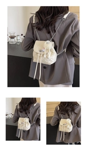 Détail d'un mini sac à dos matelassé crème avec bandoulière chaîne et breloque pompon