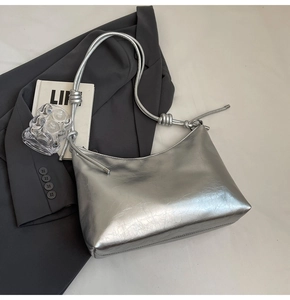 Close-up of metallic silver hobo bag with pleated texture and decorative knot strap