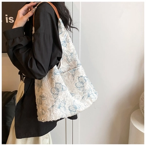Detail of embroidered butterfly tote bag featuring frayed edges and brown leather straps