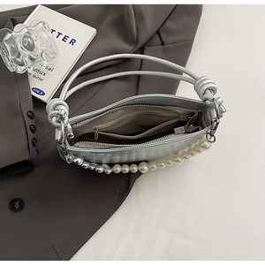 Detail view of silver metallic handbag with pearl strap and internal zipper pocket
