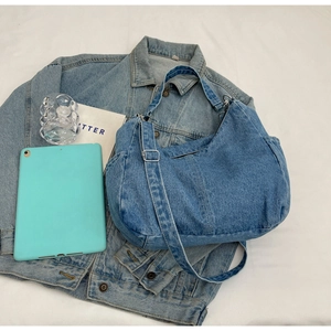 Détail rapproché du sac hobo en denim bleu avec bandoulière réglable et poche latérale