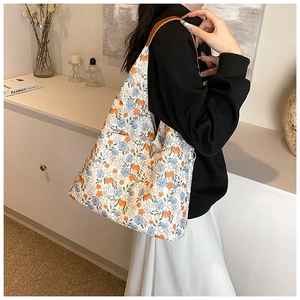 Detail of floral embroidered canvas tote bag with brown leather shoulder straps