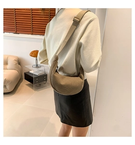 Model view of a dark khaki corduroy crescent bag with adjustable wide strap on shoulder