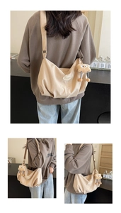 Detail of beige hobo bag with wide strap and plush monster charm decoration