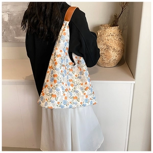 Detailed back view of a large floral tote bag with brown leather straps worn by a model