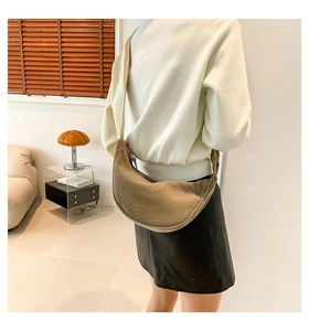 Detail of khaki corduroy crescent bag showing vertical texture and wide strap on model