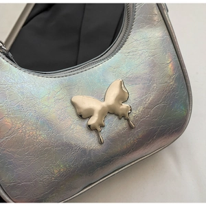 Dettaglio della borsa argento olografico con farfalla metallica e texture cracklé