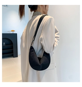 Detail of black corduroy dumpling bag featuring fine ribbed texture and adjustable strap