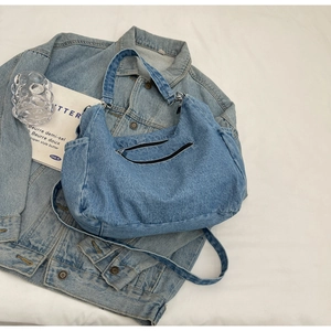 Détail du sac bandoulière en denim bleu clair avec poche zippée externe et poches latérales