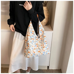 Close-up of floral tote bag featuring blue and orange embroidery with leather handles