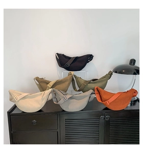 Detail view of multi-color corduroy crescent bags with adjustable straps on a shelf