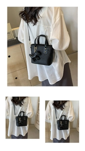 Detail of black mini handbag with lychee texture and cute dog-shaped charm accessory