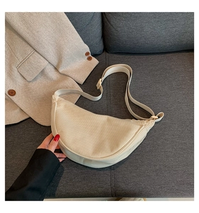 Detail of cream corduroy dumpling bag texture resting on a cozy sofa scene