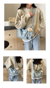 Detail of light blue canvas tote bag with wide strap and plush bear charm decoration