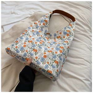 Close-up of floral embroidery texture and dark brown leather handle on a hobo tote bag