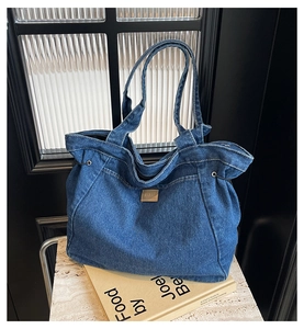 Detail der blauen Denim-Tasche mit braunem Lederpatch und Kordelzug-Verschluss
