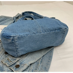 Détail de la base large et des coutures sur un sac à bandoulière en denim bleu délavé