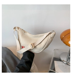 Detail view of cream corduroy dumpling bag featuring fine ribbed texture and strap