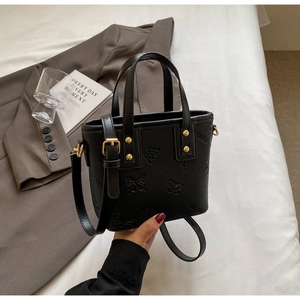 Close-up of black butterfly embossed mini bucket bag with gold studs and PU leather texture