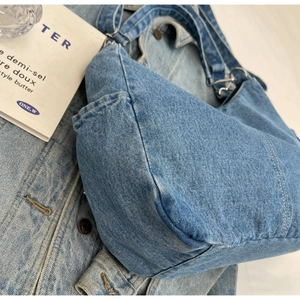 Détail du sac en jean bleu délavé avec anneaux en métal argenté et bandoulière