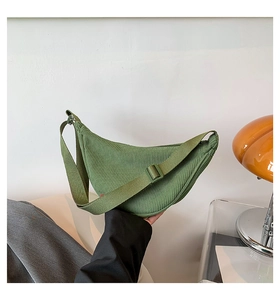 Detail of green corduroy dumpling bag with adjustable strap and textured striped fabric