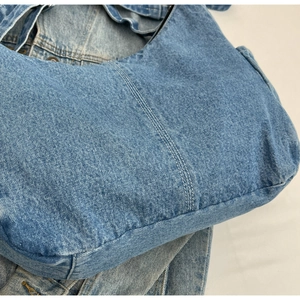 Détails de couture et texture du tissu en denim délavé bleu clair pour ce sac cabas