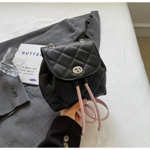 Détail d'un sac à dos en cuir matelassé noir avec bandoulière rose et fermoir métallique