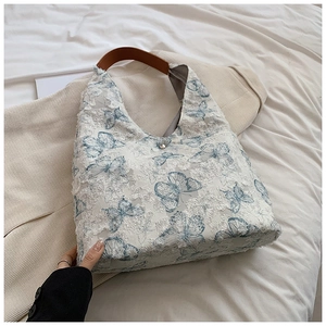 Detail view of white butterfly embroidery tote with lace fringe and leather handle