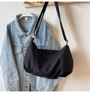 Detail of a black nylon crescent shoulder bag featuring adjustable strap and fashion patch
