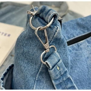 Détails des boucles métalliques et de la texture denim du sac à bandoulière décontracté