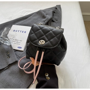 Détail d'un sac à dos matelassé noir avec fermoir métallique et bretelles roses