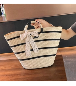 Close-up of woven straw tote bag featuring round handle and lace bow detail