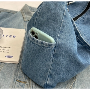 Détail d'un sac à bandoulière en denim avec une poche latérale pour téléphone portable
