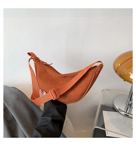 Detail of orange corduroy crescent shoulder bag with adjustable strap and textured fabric