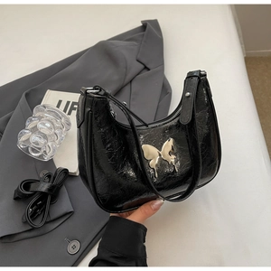 Dettaglio della borsa hobo nera plissettata con fibbia decorativa a farfalla in metallo