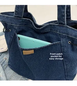 Detail der dunkelblauen Denim-Einkaufstasche mit Fronttasche, Logo und Tablet-Fach