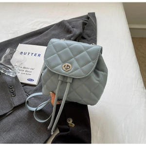 Détail d'un sac à dos matelassé bleu clair avec fermoir rotatif argenté et cordon de serrage