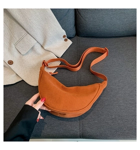 Detail of orange corduroy crescent bag showing vertical texture and adjustable strap