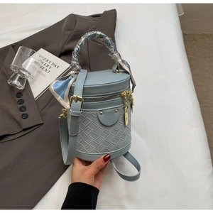 Detail of light blue woven bucket bag with floral scarf handle and gold zipper closure