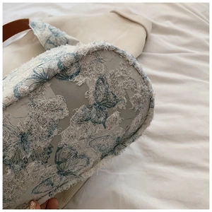 Detail of blue and white butterfly embroidery on a textured tote bag with fringe