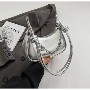 Detail of silver metallic hobo bag featuring fine chain and pearl charm on leather