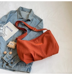 Detail view of orange tote bag with pleated texture and cute plush toy keychain