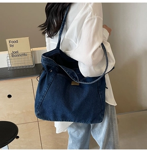 Detail einer großen dunkelblauen Denim-Tragetasche mit Kordelzug und Schultergurt-Design